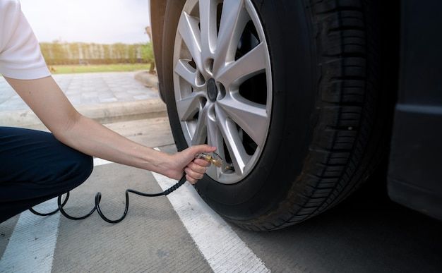 This may contain: a woman is plugging up her car's tire with an electric charger